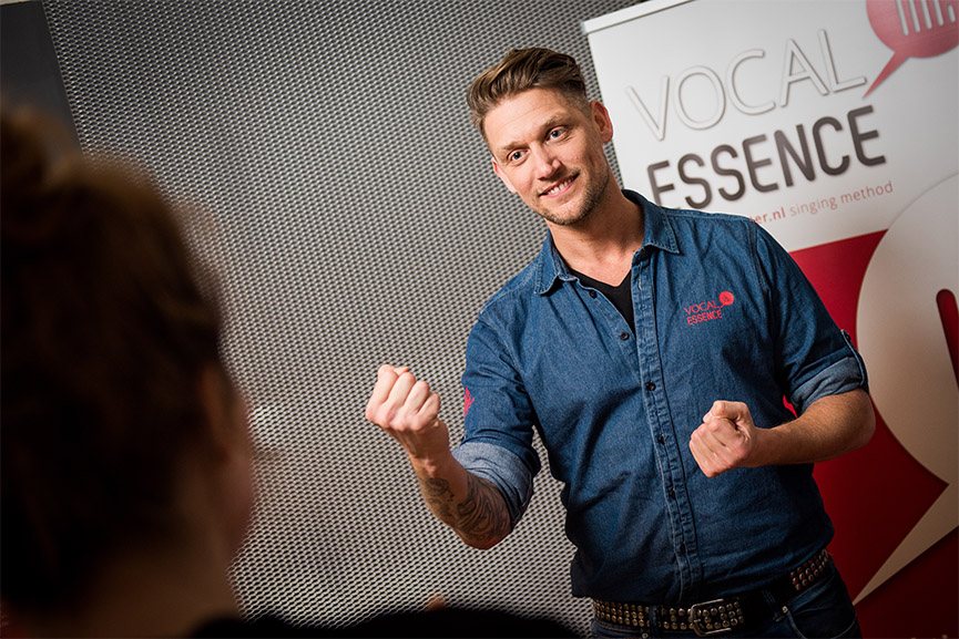 Marcel Swerissen geeft zangles, met zijn handen uitleggend voor een leerling.
