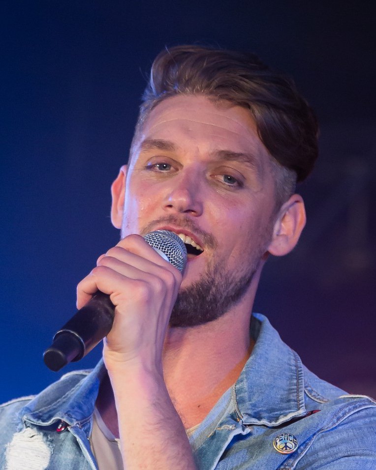 Marcel Swerissen zingt in een microfoon op het podium.